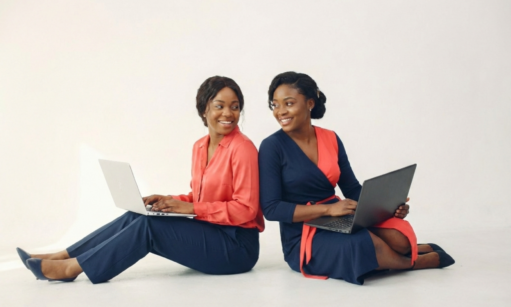 two woman workers for ashaelonline IT Support and services sitting withe their laptops on their thighs.